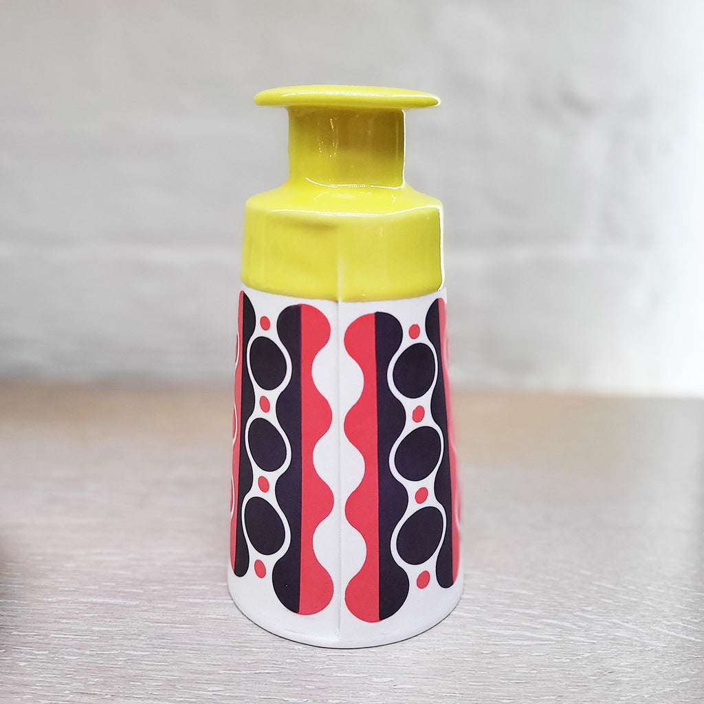Rear view of Slab-built Big Cone Bottle by Contemporary Ceramicists MapMap. Has a distinctively mid-centurary modern feel - this piece is predominently white background with navy and red pattern and a yellow top section.