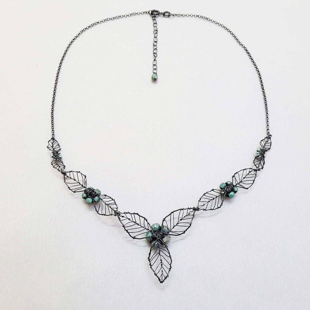 reverse side of Handmade statement bridal necklace by Judith Brown Bridal depicting folliage with delicate blue accent glass beads. Ideal to wear for your special day