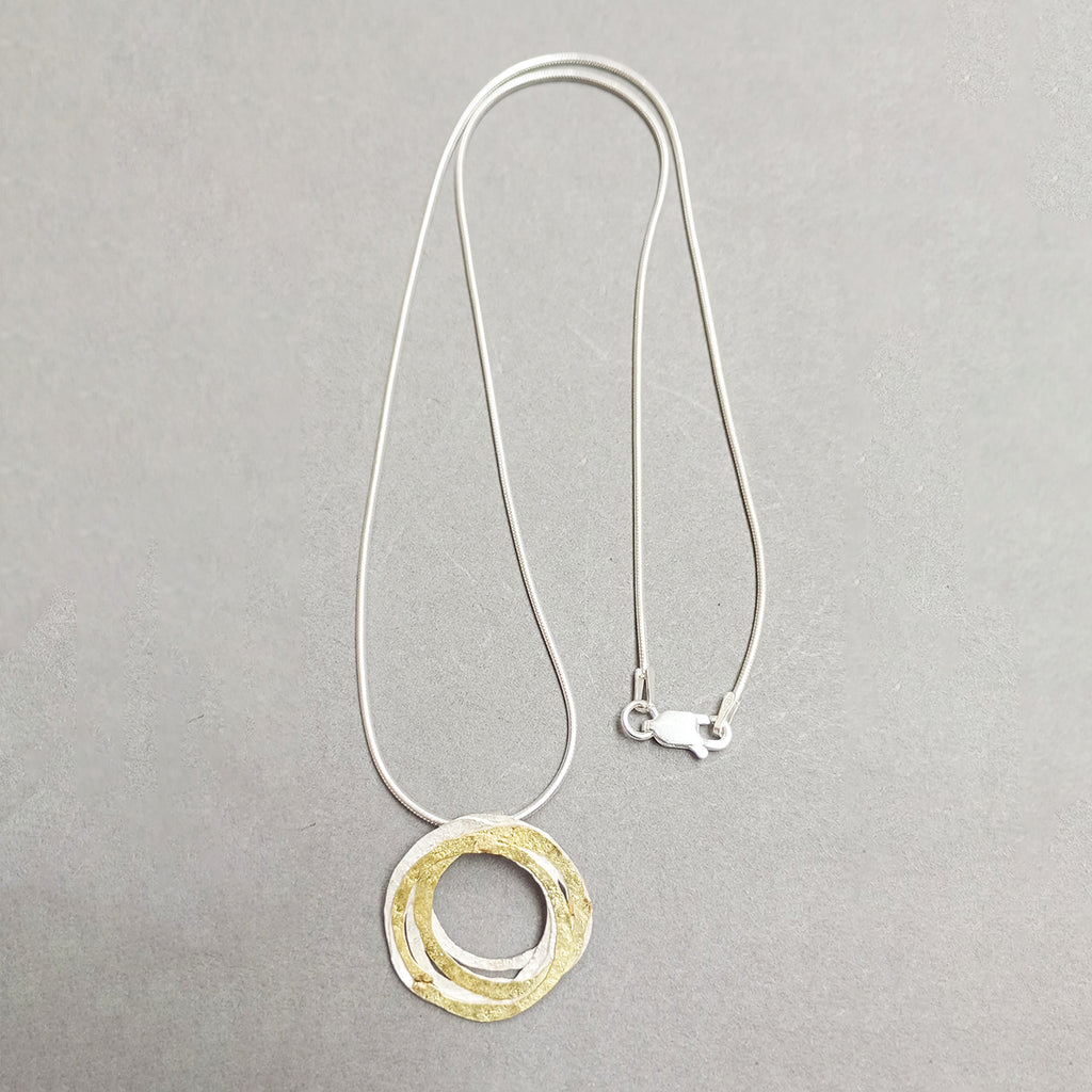 pendant inspired by birds nests and natural structures.  Silversmith and jewellery designer Shimara Carlow has created individual hammered and textured silver and gold circles assembled into a wrapped nest, and hanging from a simple snake chain.