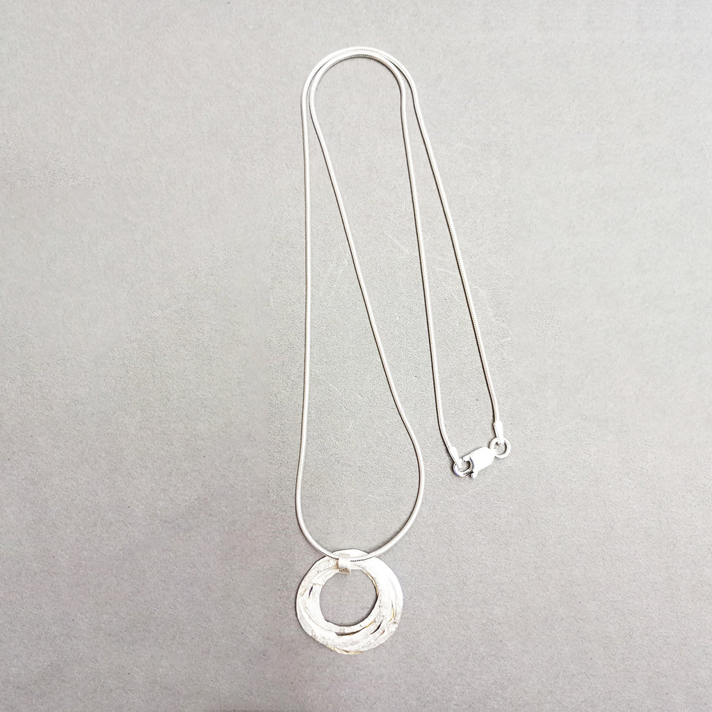 pendant inspired by birds nests and natural structures.  Silversmith and jewellery designer Shimara Carlow has created individual hammered and textured silver and gold circles assembled into a wrapped nest, and hanging from a simple snake chain.