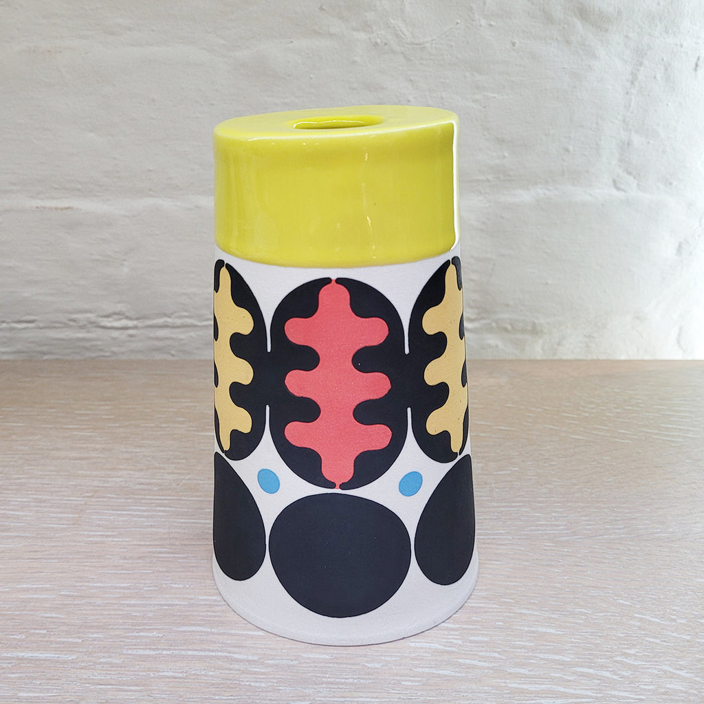 Large Flat Top Cone Vase decorated using stencils and slip colours. With a distinctively mid-centurary modern feel about it - this piece is predominently white background and navy with red, blue and peach accents and a yellow top section. It is by contemporary ceramics duo MapMap