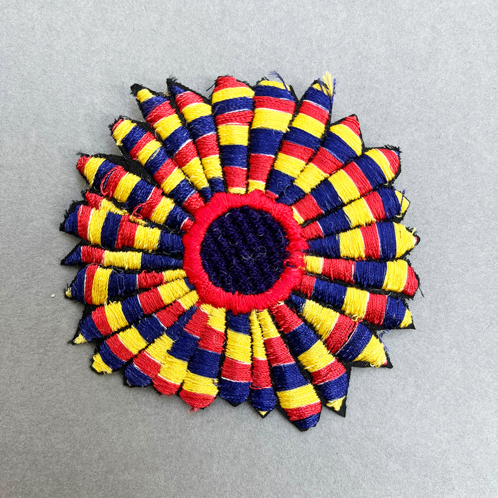 A beautiful machine embroidered brooch by Michael Brennand -Wood, with a hand-painted presentation box.  The brooch is red, blue and yellow