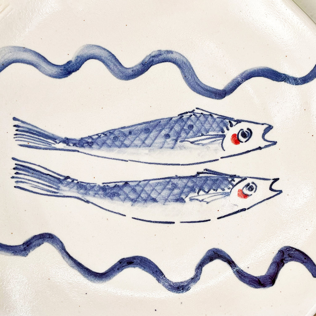 detail of the hand painted graphic on A beautiful round serving dish made from white-glazed stoneware and hand decorated with two cobalt blue fish.
