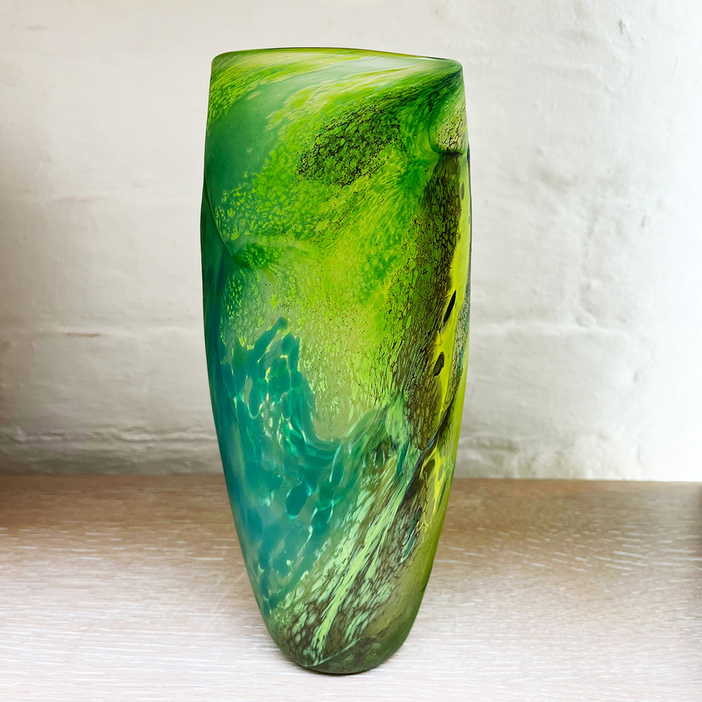 Green glass vase from Will Shakspeare's 'Random Trails' range, inspired by walking in the Elan Valley in Wales.  This vase is predominently green with varying shades, plus blue and yellow highlights shown in this view