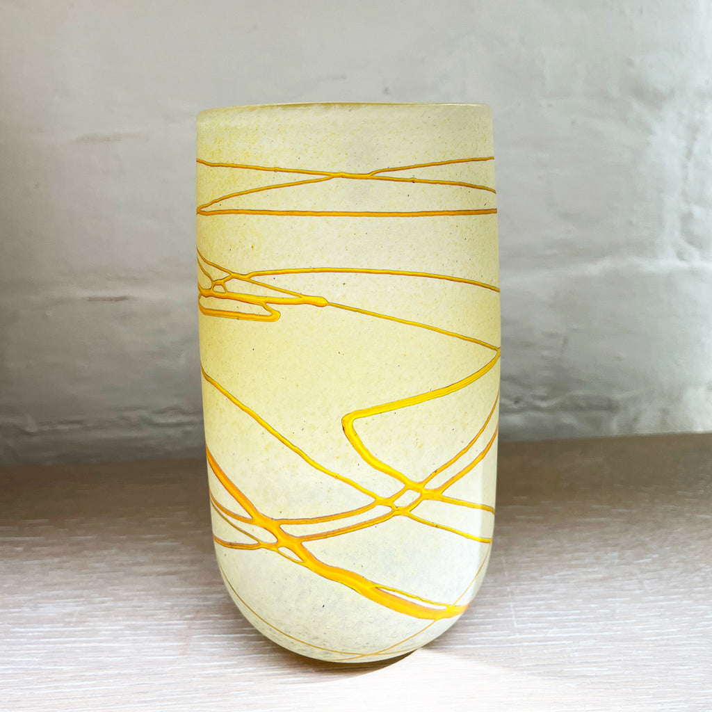 A medium vase from Will Shakspeare's 'Random Trails' range, inspired by walking in the Elan Valley in Wales.  This vase is predominently a vanilla colour with threads of gold colour. Will has been making his own inimitable glassware for nearly 30 years and is one of the country's most collected makers