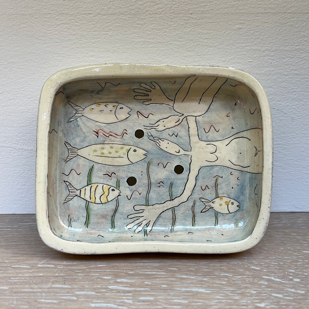 Blue soap dish, decorated with figurative illustrations using coloured slips, brushwork, stencils and sgraffito on red earthenware. Contemporary Ceramicist Vivienne Ross's unique illustrations contain an element of humour. This dish features 2 figures in a sea of fish and plants