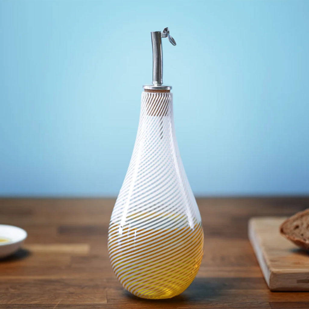 A small bottle for drizzling olive oil, fitted with a cork pouring spout and embodying the Benefield Spencer signature white filigrana cane pattern. Shown in the kitchen