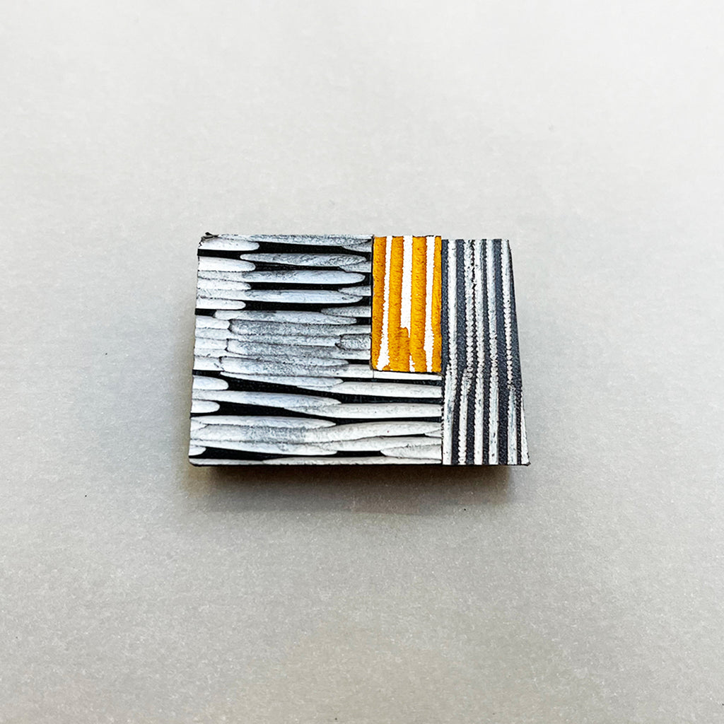Orange brooch with grey and black in hand carved and dyed leather by Janine Partington