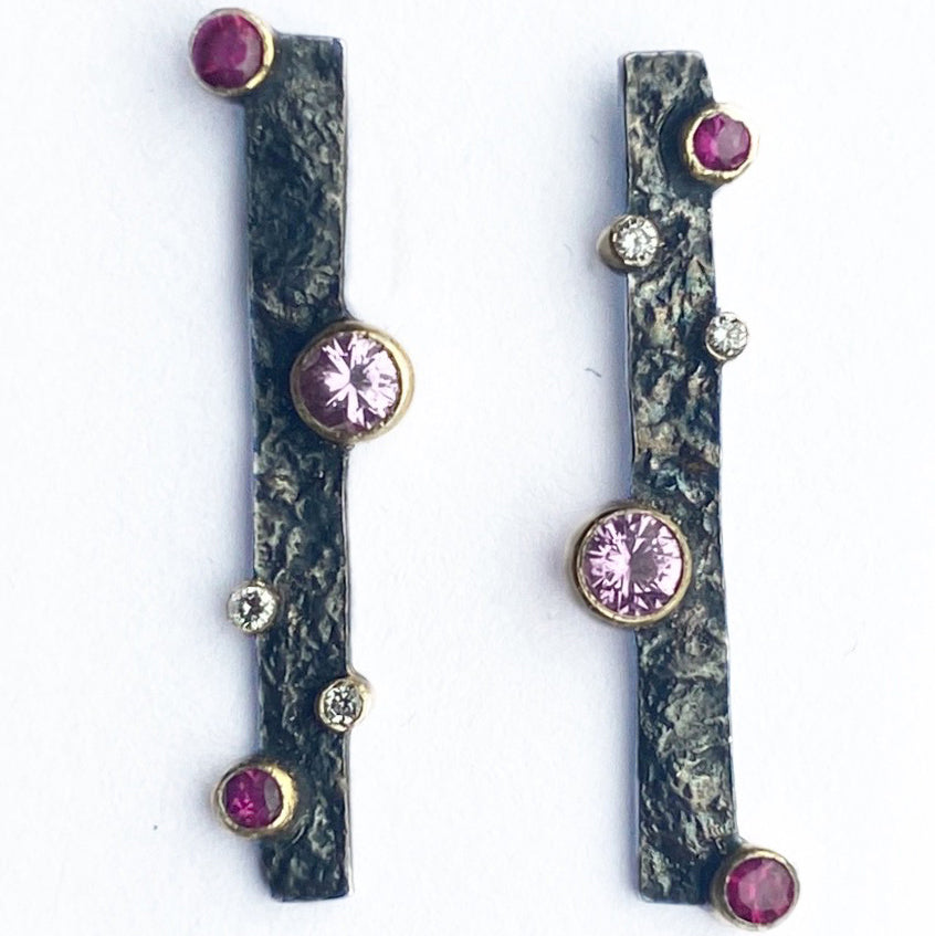 Close up of sterling silver drop studs with texture and pink sapphire, ruby and lab diamonds by Contemporary Jeweller Sam Holmes