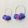 Side view of beautiful hoop earrings adorned with three small, decorated paper cubes by Rike Lenzing in purple, blue and cerise 