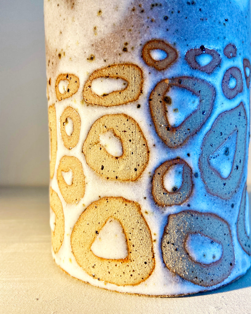 Close up of cylindrical vase in flecked stoneware clay, simply finished with a loosely applied off-white matte glazeby Contemporary Ceramicist Sarah Bartlem