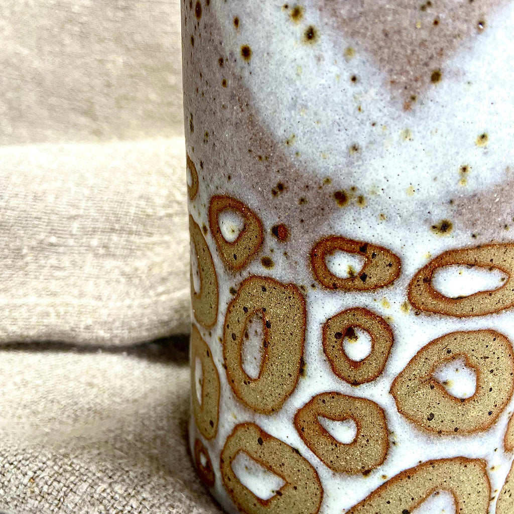 Close up detail of cylindrical vase in flecked stoneware clay, simply finished with a loosely applied off-white matte glazeby Contemporary Ceramicist Sarah Bartlem