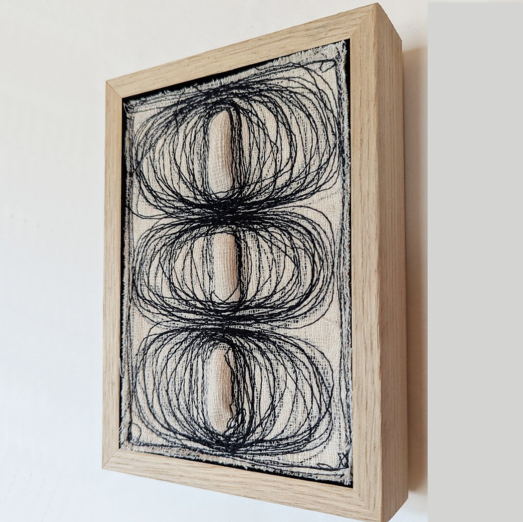textile design with monochromatic stitches and fabric, creating three ovals that pop out of the canvas by Contemporary irish textile artist Patricia Kelly