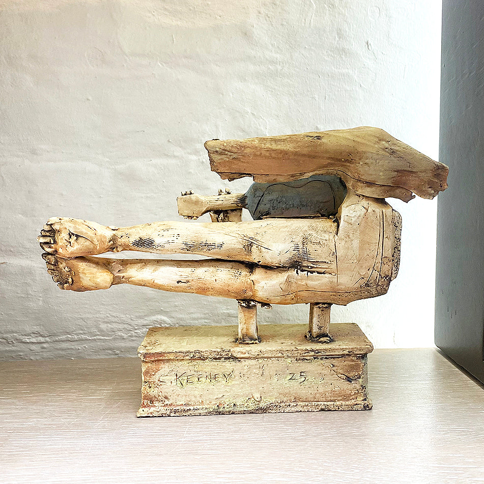 rear of sculpture of a flying figure playing a guitar inscribed with “I’m Going Where the Wind Takes Me” slab-built by contemporary ceramicist Christy Keeney