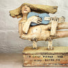close up of sculpture of a flying figure playing a guitar inscribed with “I’m Going Where the Wind Takes Me” slab-built by contemporary ceramicist Christy Keeney