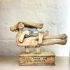 sculpture of a flying figure playing a guitar inscribed with “I’m Going Where the Wind Takes Me” slab-built by contemporary ceramicist Christy Keeney