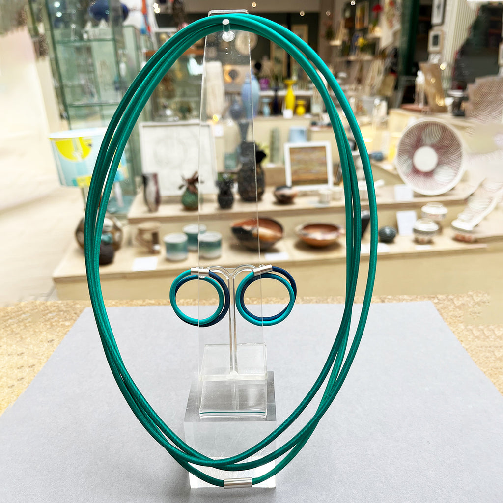 contemporary blue green double loop earstuds are the perfect way to add a pop of colour to any outfit. In silver and hand dyed elastic by Gilly Langton.  Photographed with the Kelp & Jade super string necklace at the Bluecoat Display Centre