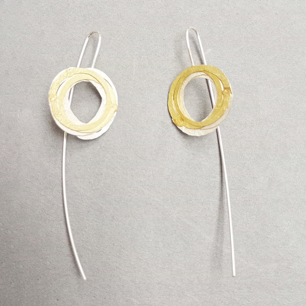 inspired by birds nests and natural structures, these earrings on long silver wires, feature individual textured silver and gold circles assembled into a wrapped nest
