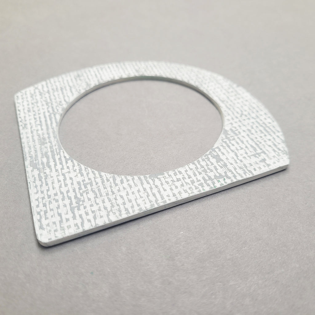 Angled photo of White and grey A-shaped bangle inspired by the Bauhaus design movement. Made from linoleum and hand painted by Studio Ditto in Liverpool