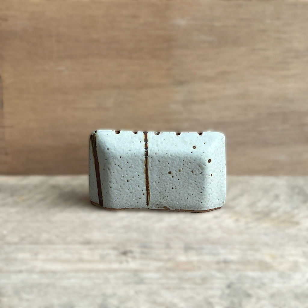 Press moulded small clay pillow, gas reduction fired stoneware. Found clay inlay and wood ash glaze to give the piece a smooth white finish by contemporary ceramicist Hannah Sulek