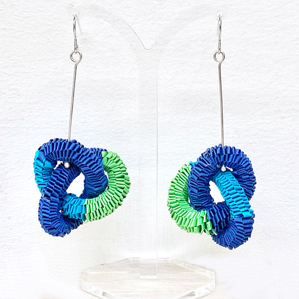 knotted paper earrings in tones of light blue, dark blue and green twisted throughout each other by Rike Lenzing at Bluecoat Display Centre