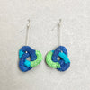 knotted paper earrings in tones of light blue, dark blue and green twisted throughout each other on grey background by Rike Lenzing