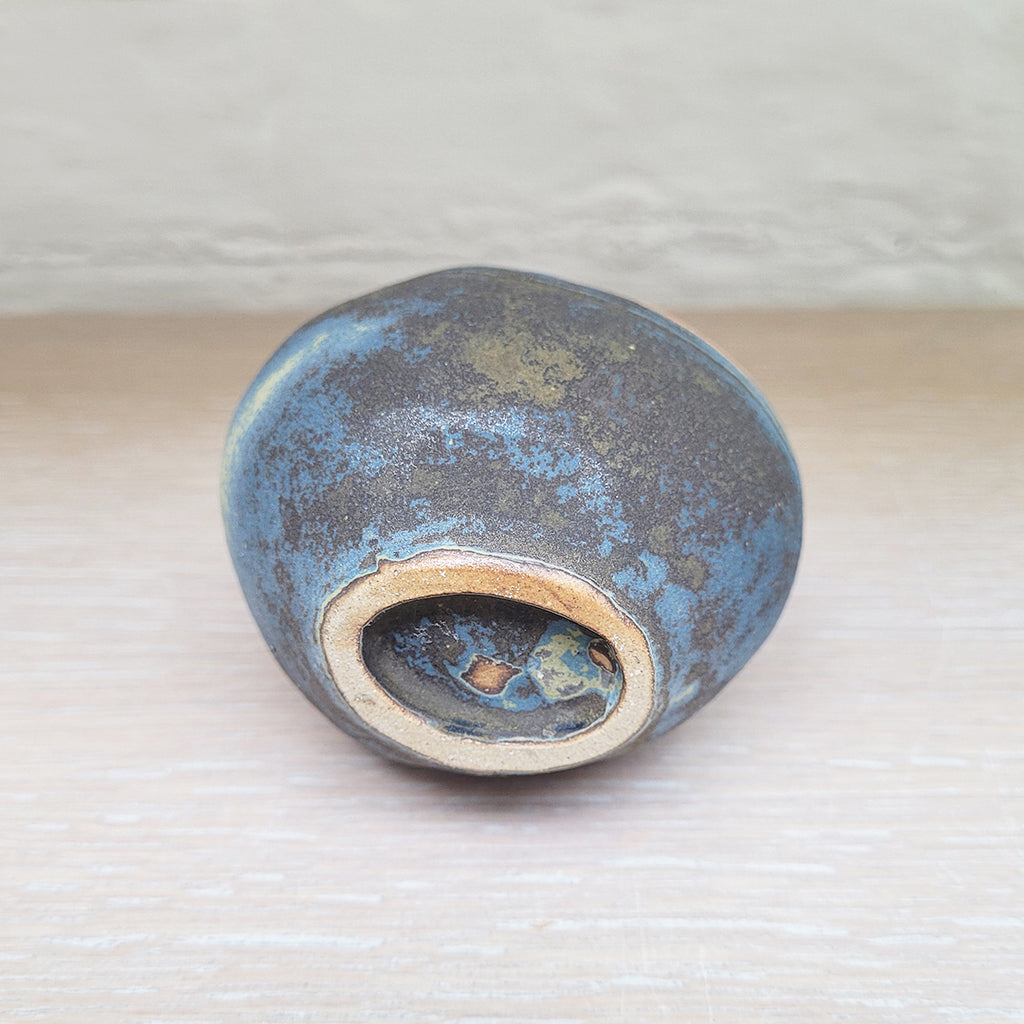 base of a stunning piece of contemporary ceramic featuring texture, deep blues and ochres. Held inside this small stoneware bottle are porcelain seashells which give a gentle rattle when shaken