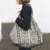 Close up of Person holding a Naturally dyed & Hand Block Printed Bag by Louisa Loakes against a textured wall.