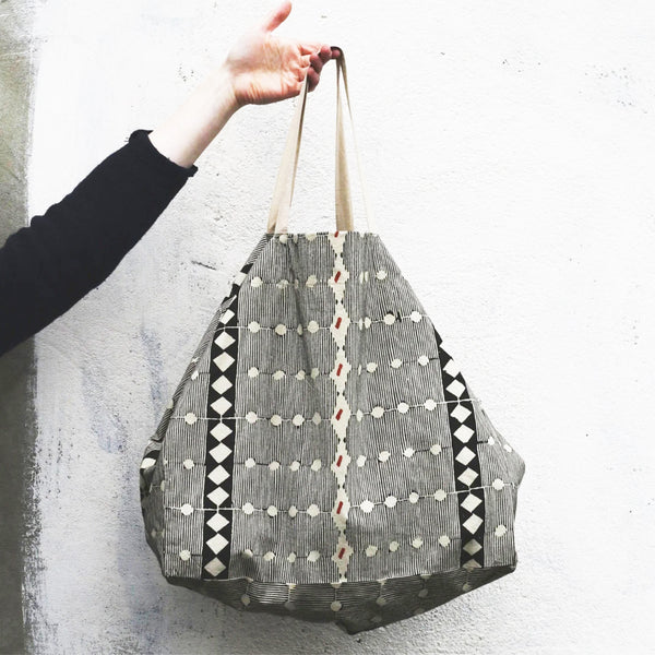 Person holding a Naturally dyed & Hand Block Printed Bag by Louisa Loakes against a light background