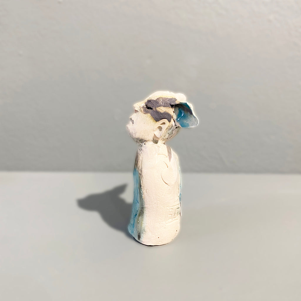 Left side view of Miniature figure with large 'listening ears' loosely inspired by creation stories, from folklore by contemporary ceramicist Sharon Griffin