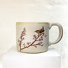 beautiful hand thrown mug adorned with a bird sitting upon a cherry blossom branch by Julia Smith.