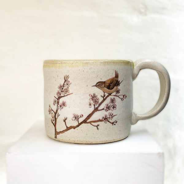 beautiful hand thrown mug adorned with a bird sitting upon a cherry blossom branch by Julia Smith.