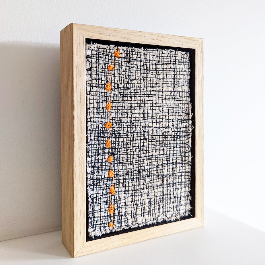 side view of Framed textile art featuring a bold design comprised of orange dots in a stitched grid by Irish textile artist Patricia Kelly