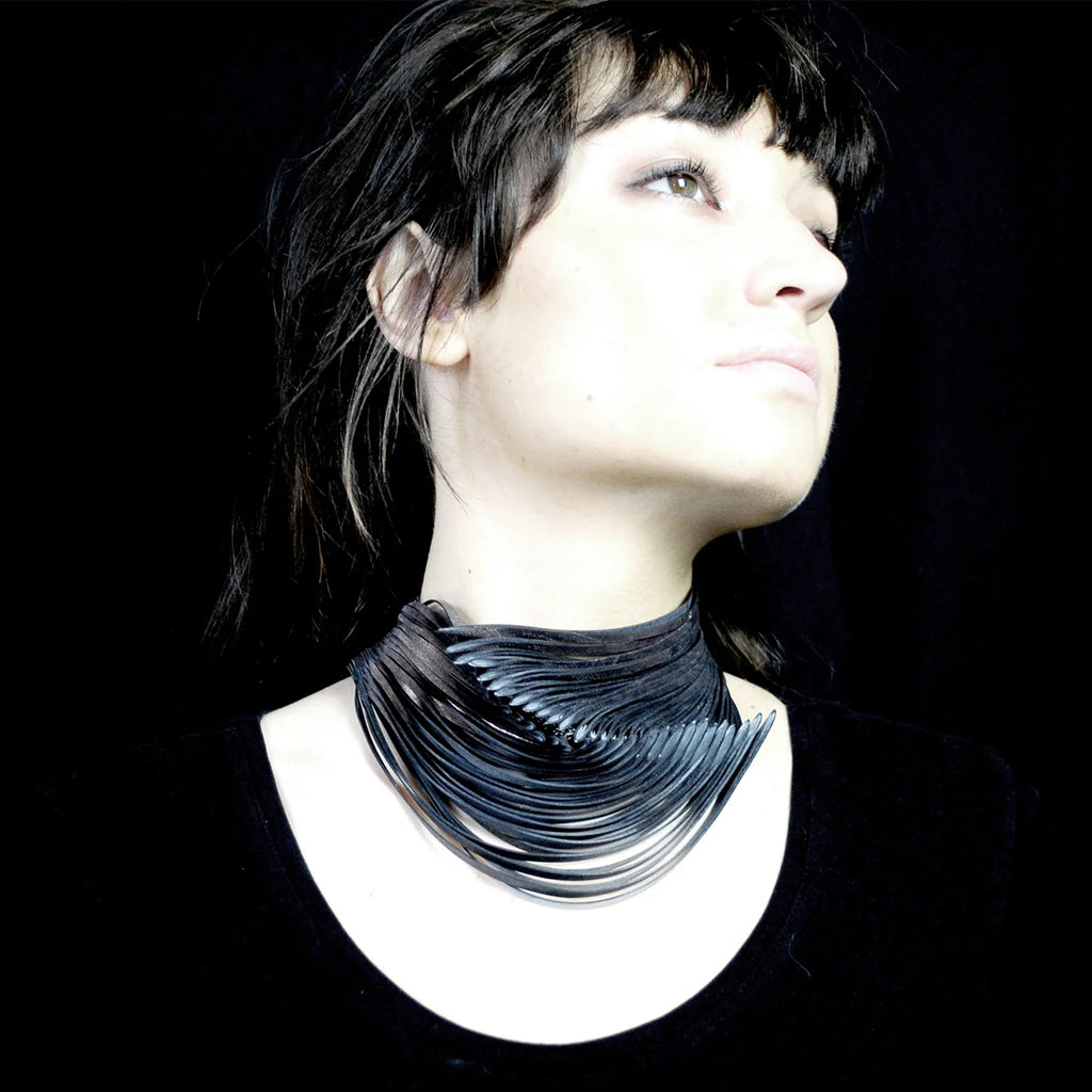 Model wearing handmade necklace out of rubber from used bicycle inner tubes finished with a delicate copper colour by Emma Ware