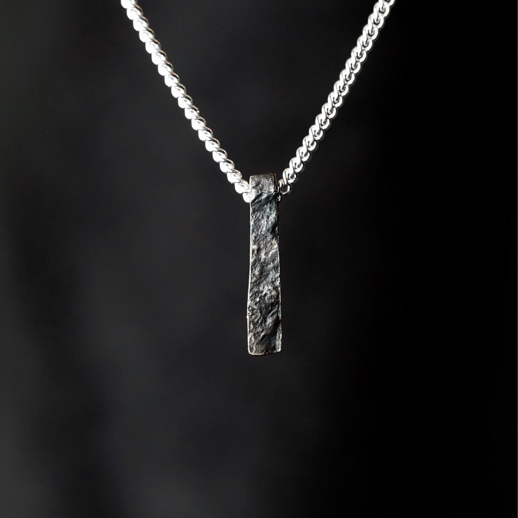 Close up of Ripples Pendant by Sam Holmes crafted from oxidised sterling silver with delicate undulations and surface textures against black background