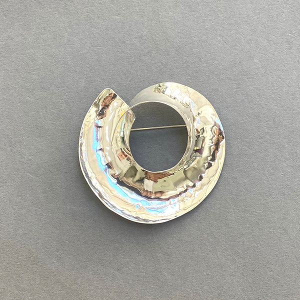 Beautiful Sterling Silver Swirled Round Brooch by irish Silversmith Kevin O’Dwyer on a grey background
