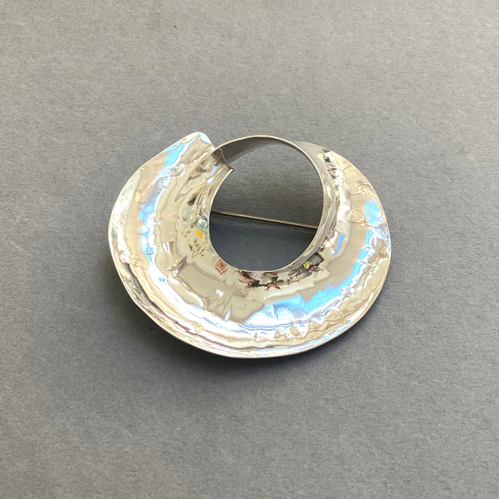 Side view of Beautiful Sterling Silver Swirled Round Brooch by irish Silversmith Kevin O’Dwyer on a grey background
