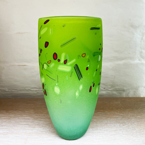 A medium cone vase by contemporary glass artist Will Shakspeare. The piece is inspired by the landscape of the Somerset Levels and is predominantly green in colour with accents in red, black and white