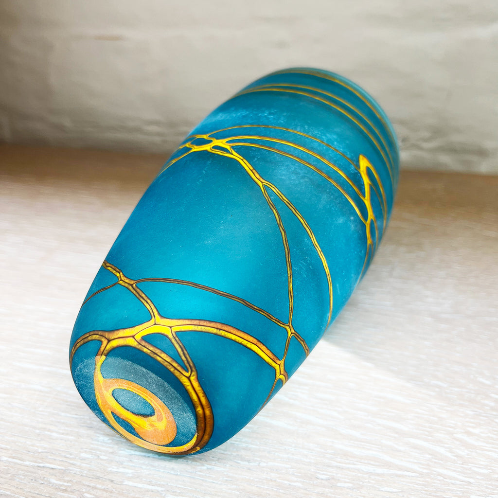 Base view of small cone vase from contemporary glass worker Will Shakspeare's 'Random Trails' range, inspired by walking in the Elan Valley in Wales.  This vase is predominently aqua blue with threads of gold colour