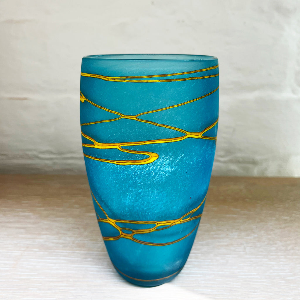 A small aqua cone vase from contemporary glass worker Will Shakspeare's 'Random Trails' range, inspired by walking in the Elan Valley in Wales.  This vase is predominently aqua blue with threads of gold colour