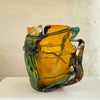 side view of 'roots' orange bowl by contemporary glass artist Will Shakspeare. The piece is inspired by trees and is predominantly orange in colour with green 'roots'. one of the country's most collected contemporary makers.