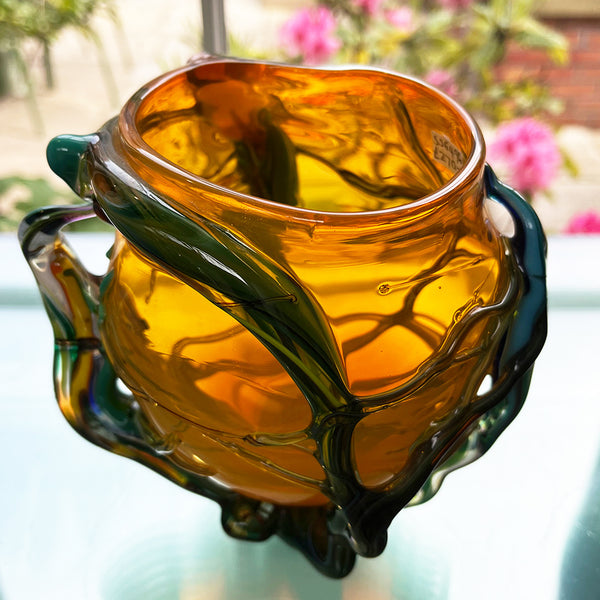 interior view of 'roots' orange bowl by contemporary glass artist Will Shakspeare. The piece is inspired by trees and is predominantly orange in colour with green 'roots'. one of the country's most collected contemporary makers.