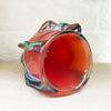 inside view of a stunning bowl by contemporary glass artist Will Shakspeare. The piece is inspired by trees and is predominantly red in colour with 'roots' in blues and a kaleidoscope of colours.