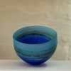 inside a small bowl by contemporary glass artist Will Shakspeare. The piece is inspired by the landscape of the Isles of Scilly and is predominantly blue in colour.