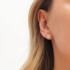 Model with long hair wearing etched silver ear studs set with 0.02ct diamonds with a post and scroll backs by Contemporary jeweller Diana Porter 