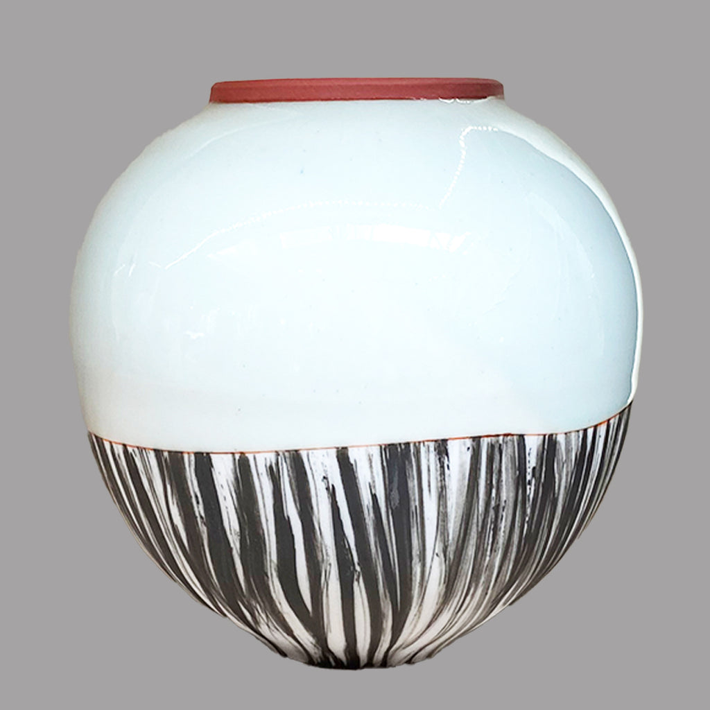 small round vase by Irish contemporary ceramicist Adam Frew with terracotta-coloured rim and painted black detailing on the bottom half 