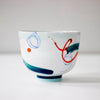 Front of White bowl with colorful abstract designs on a white background by Irish Contemporary Ceramicist Anam Frew