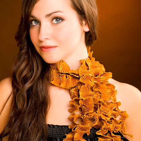 Woman wearing Spiral Pleat Copper ruffled scarf by Nawal Gebreel against a brown background