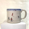 beautiful hand thrown ceramic mug featuring a winter scene with people sledging in the snow by Julia Smith