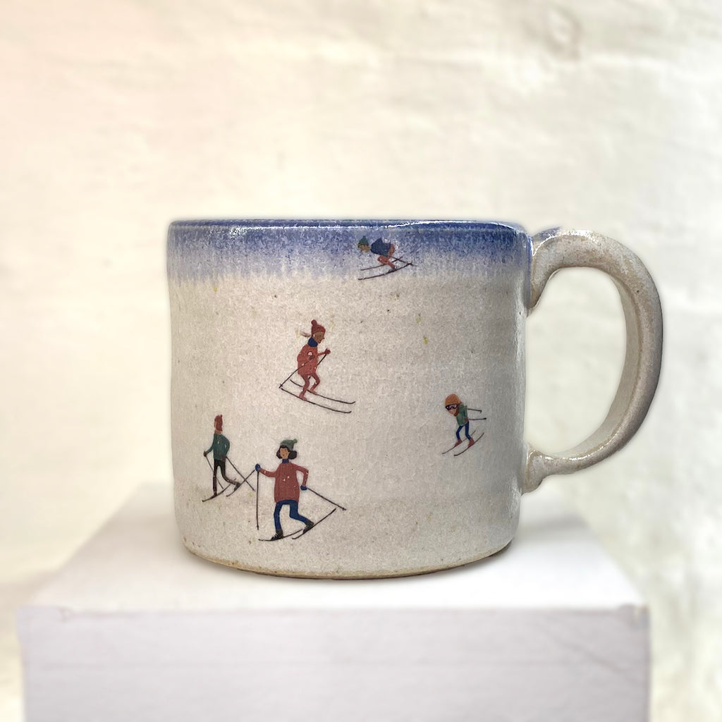 beautiful hand thrown ceramic mug featuring a winter scene with people sledging in the snow by Julia Smith